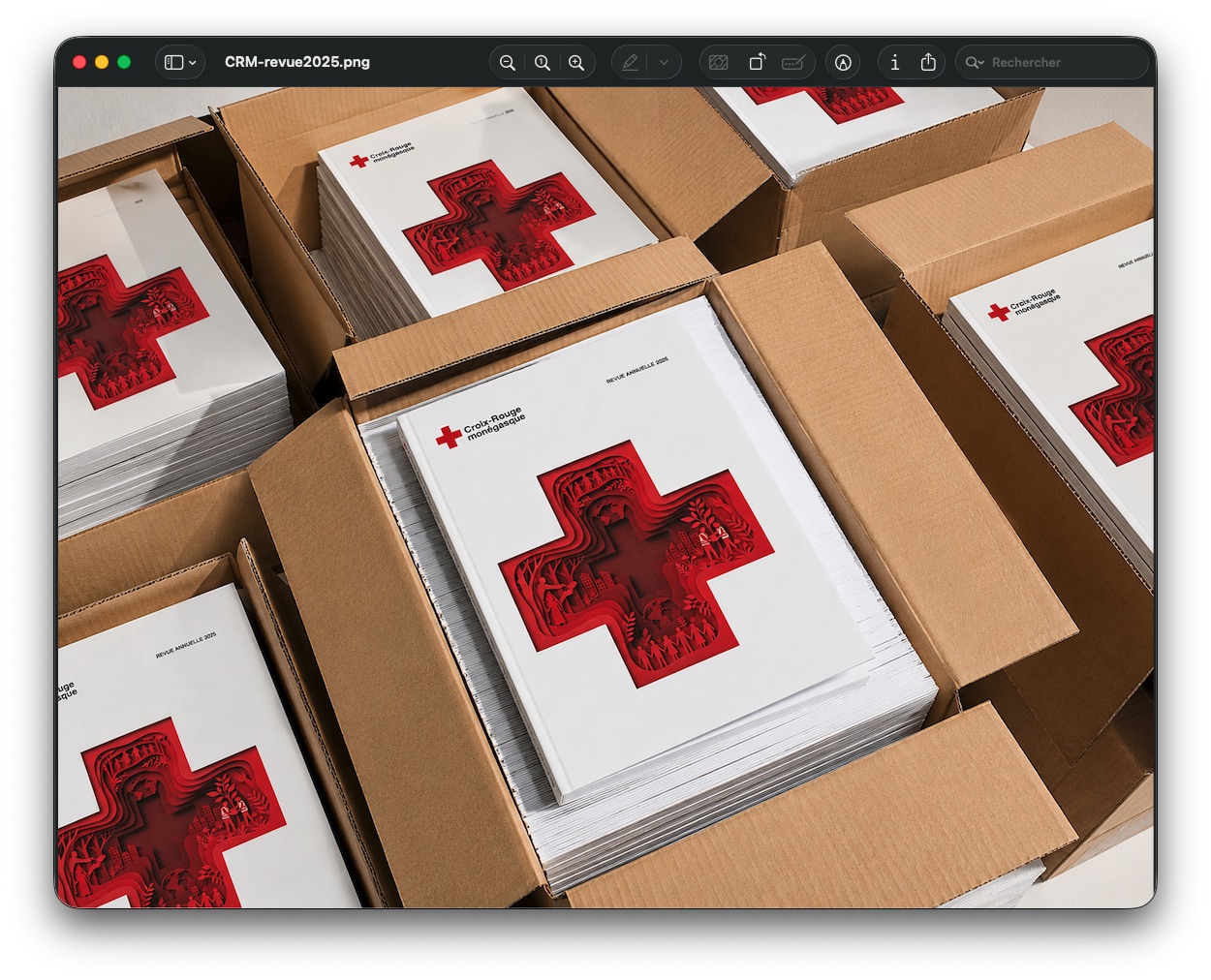 Visuel de revues annuelles 2025 de la Croix-Rouge monégasque disposées dans des cartons, avec leur couverture illustrée.