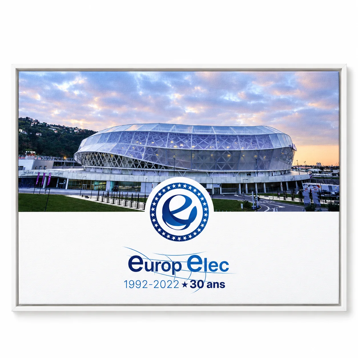 Affiche Europelec 30 ans, 1992–2022, avec photographie du stade et logo bleu, présentée de face dans une caisse américaine blanche.