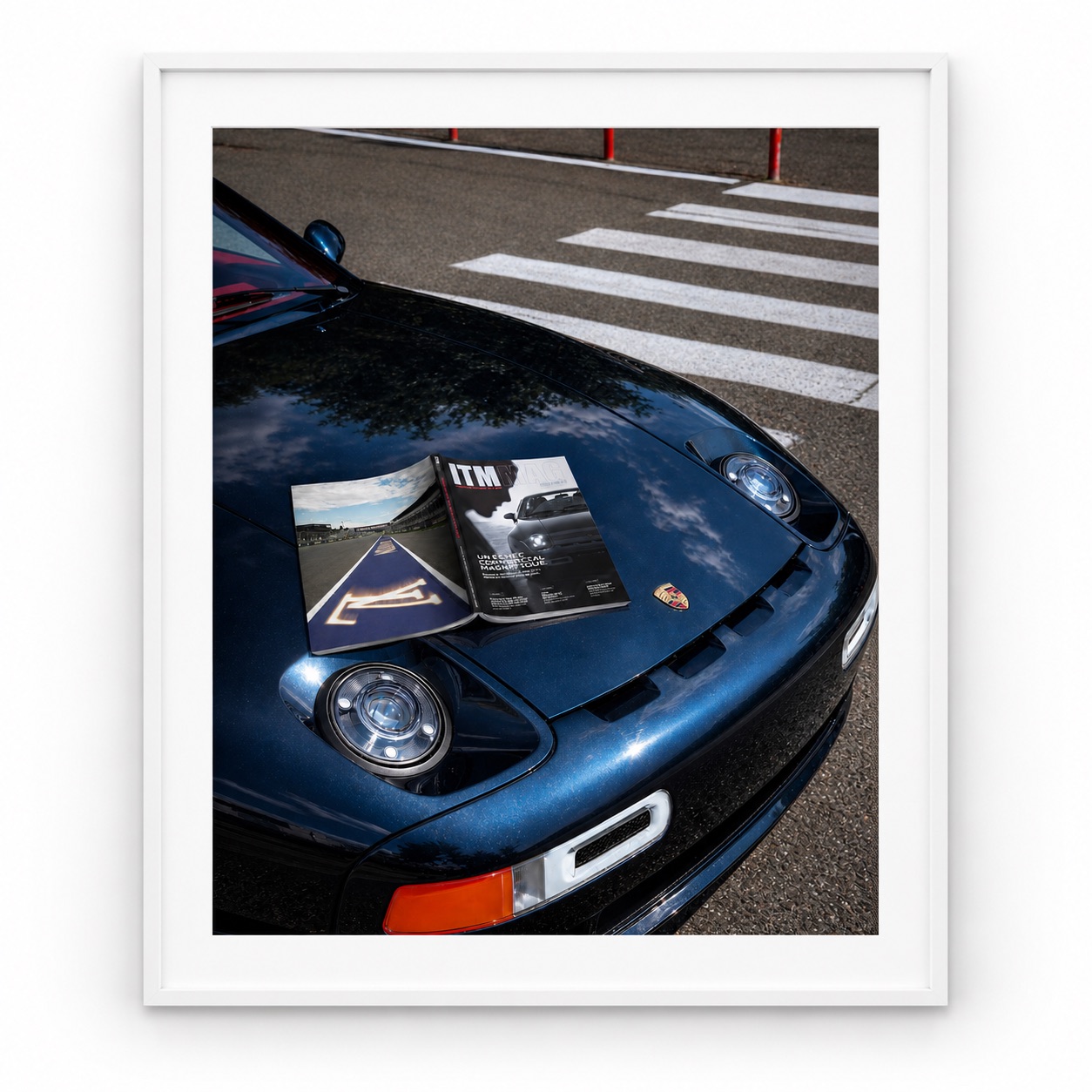 Magazine pédagogique ITM MAG ouvert sur le capot d’une Porsche bleue, présenté sous cadre blanc.