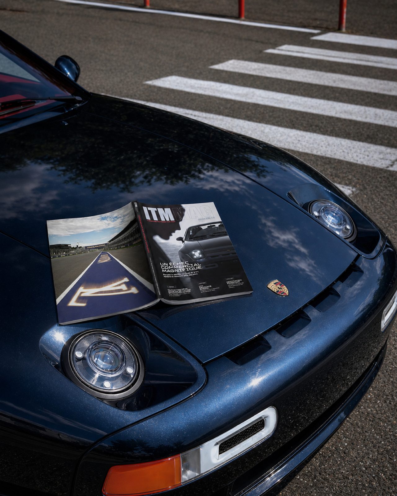 Mise en scène du magazine pédagogique ITM MAG ouvert sur le capot d’une Porsche.