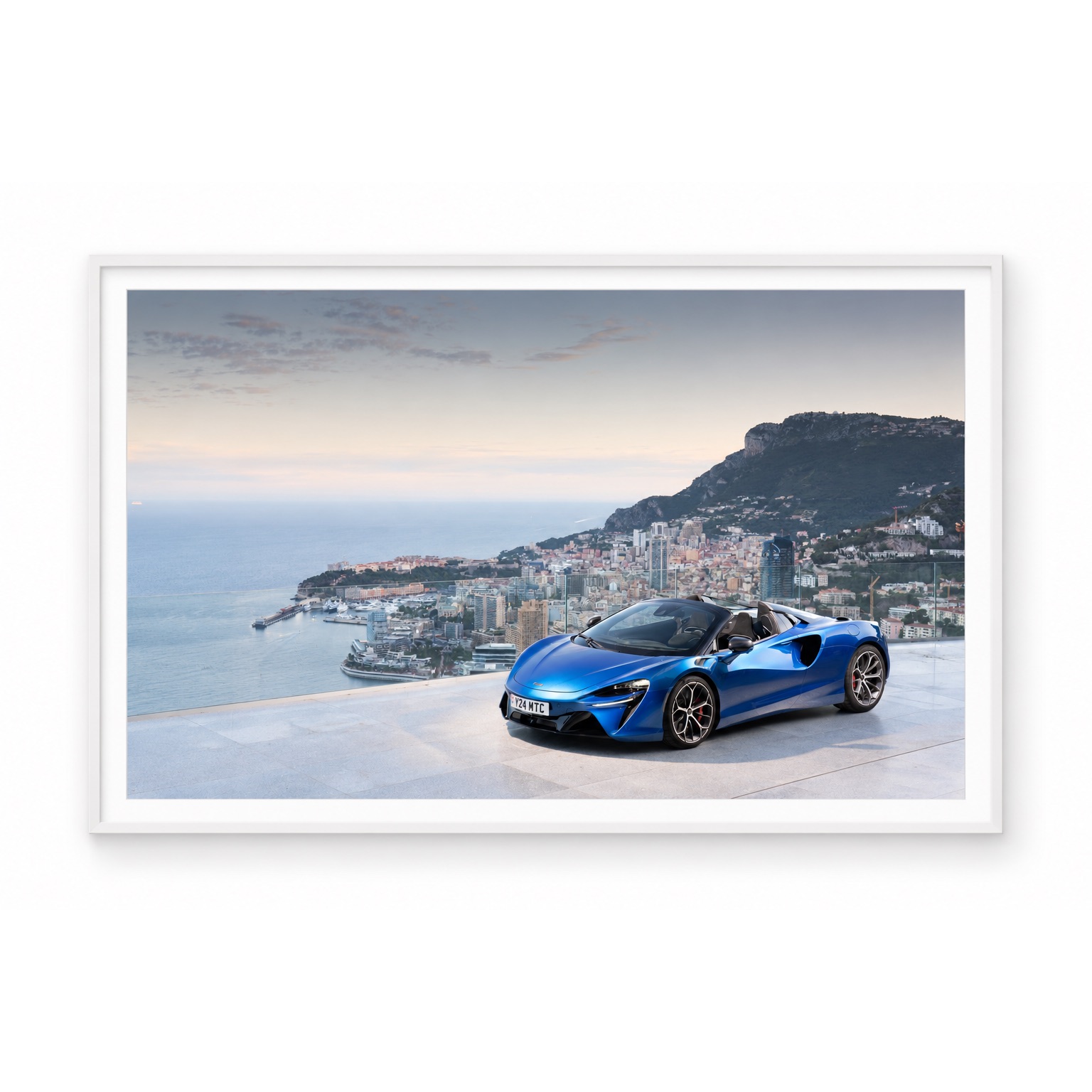 McLaren Artura Spider bleue devant le panorama de Monaco, présentée sous cadre blanc.